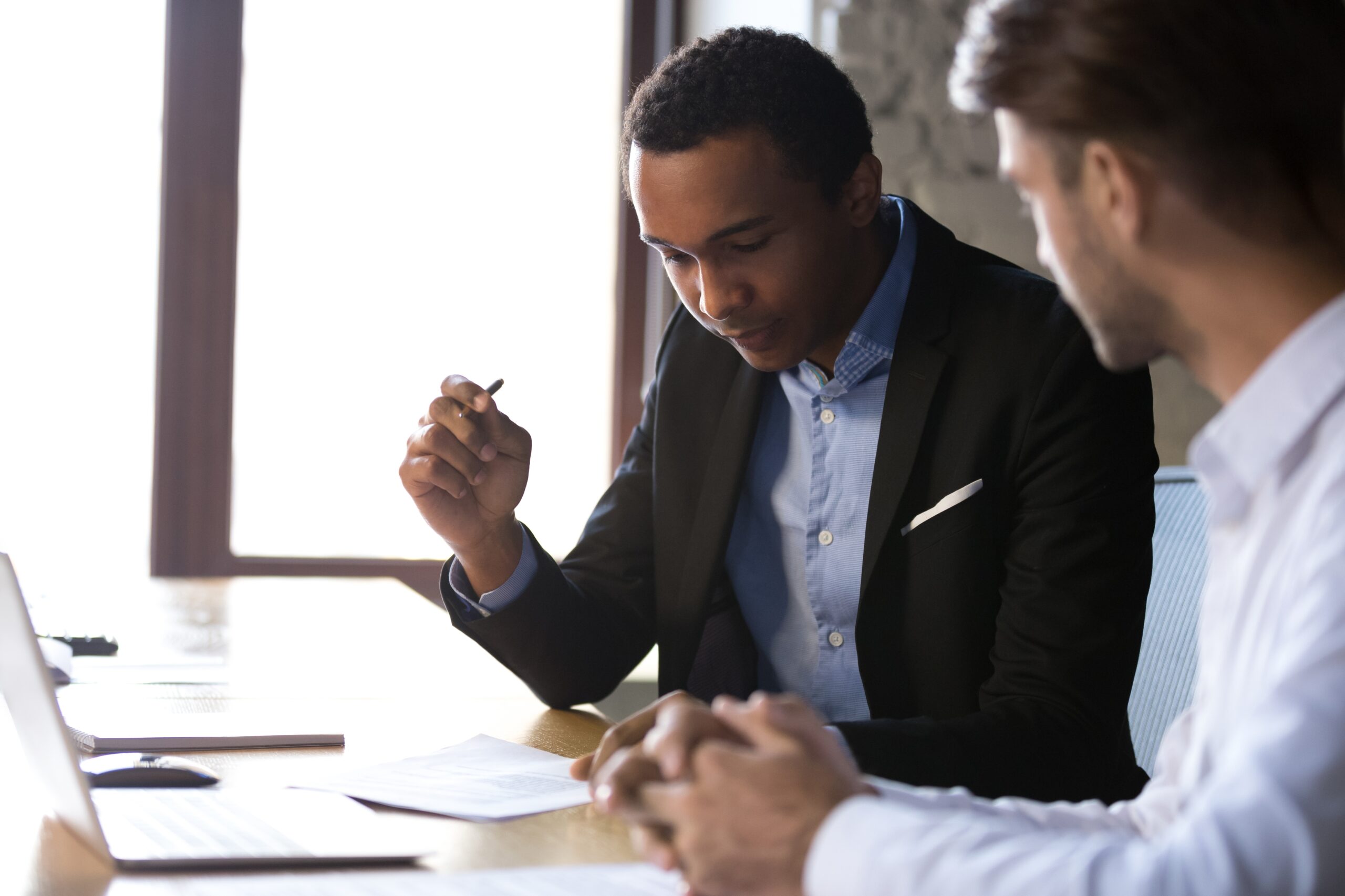 Two men discussing information on a paper.